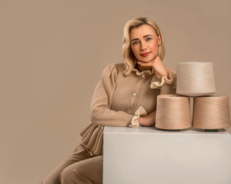 Fundadora de Michiada posando con bobinas de hilo premium para la creación de prendas de punto artesanal.